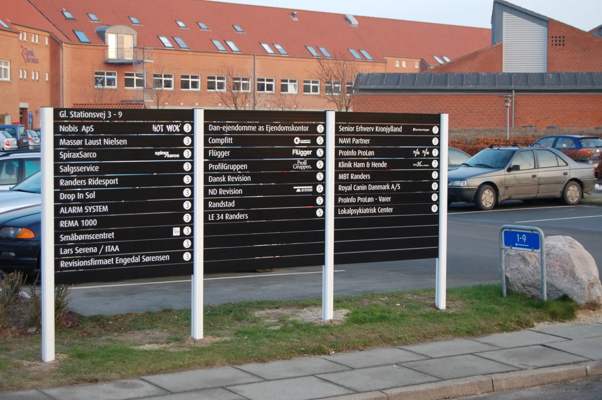 Stor udendørs vejvisningspylon med flere virksomhedsnavne